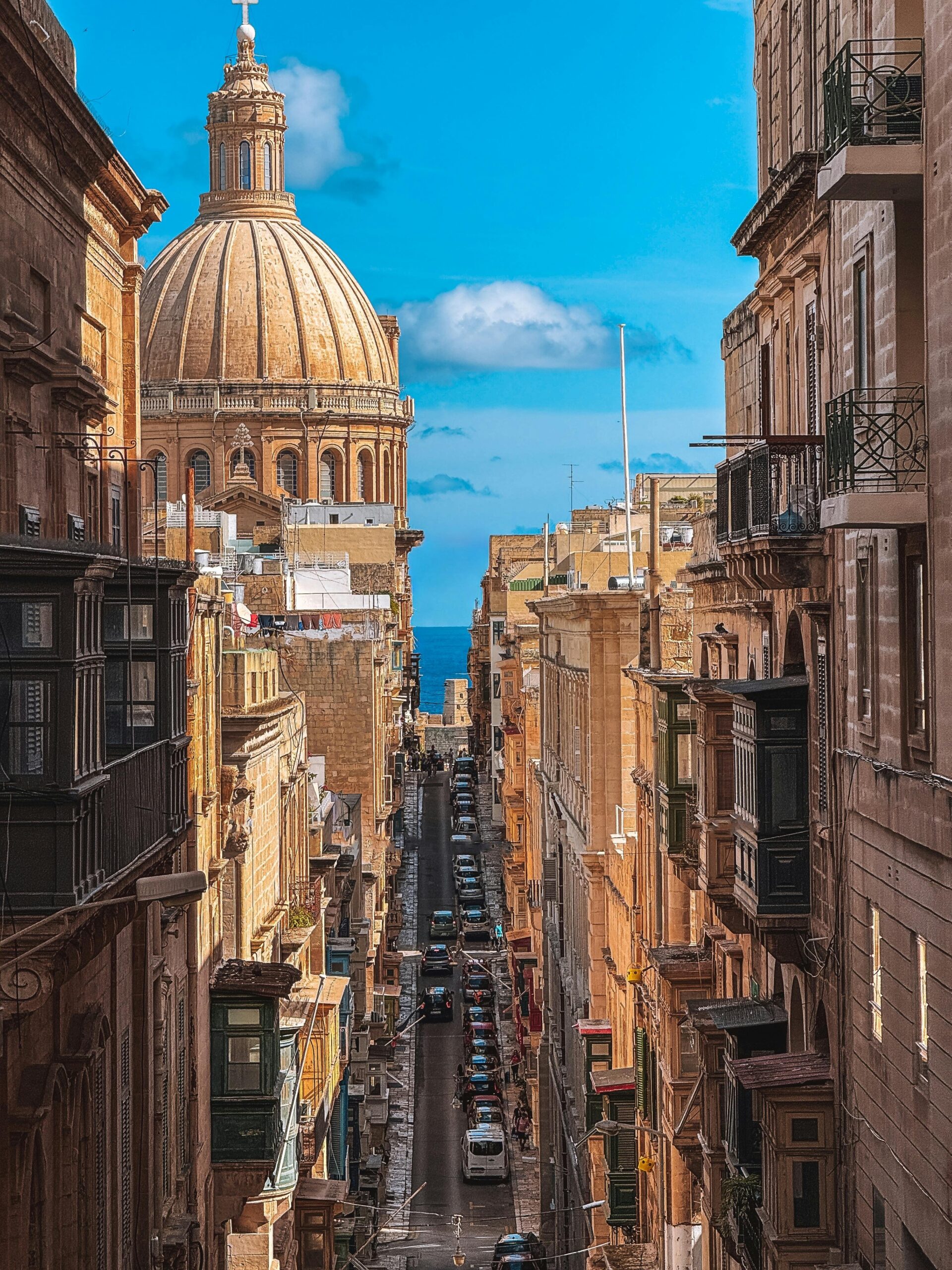 Stunning view of a narrow street in Valletta, Malta with historic architecture and a blue sky.